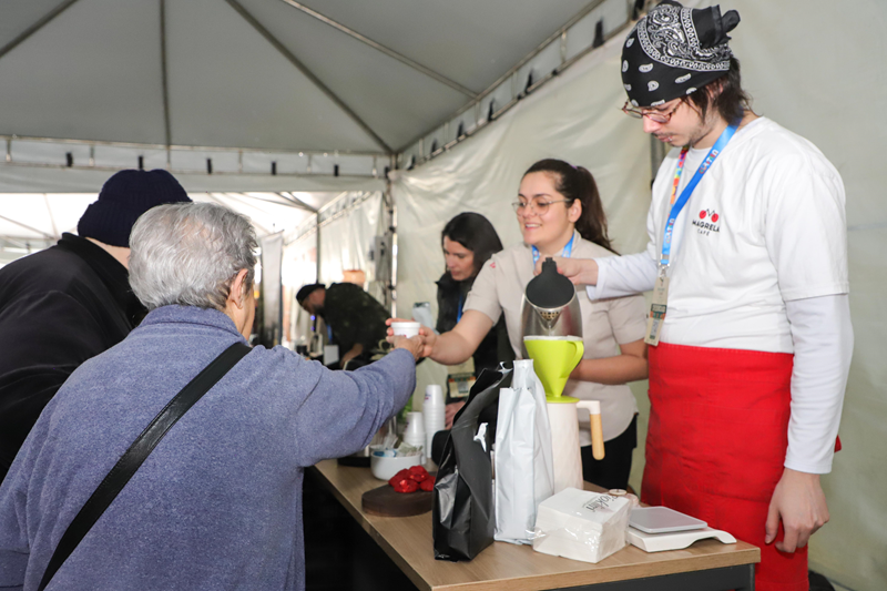 Equipe prepara e serve café aos visitantes na tenda do festival.